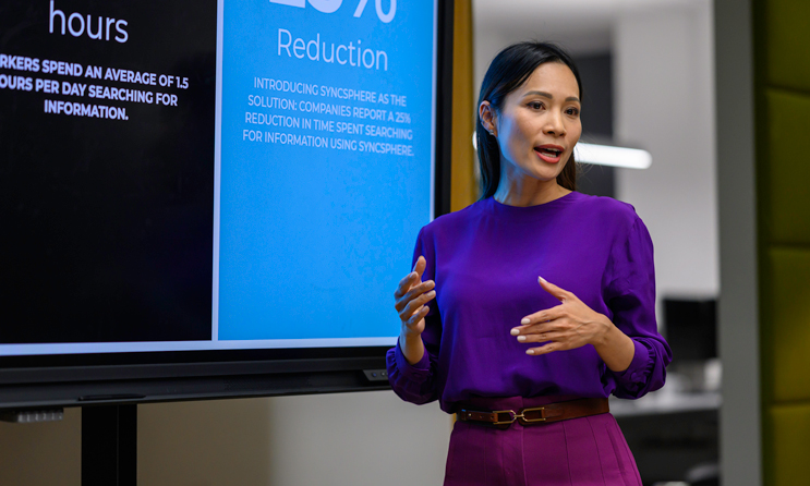 Businesswoman giving presentation on device screen during meeting.