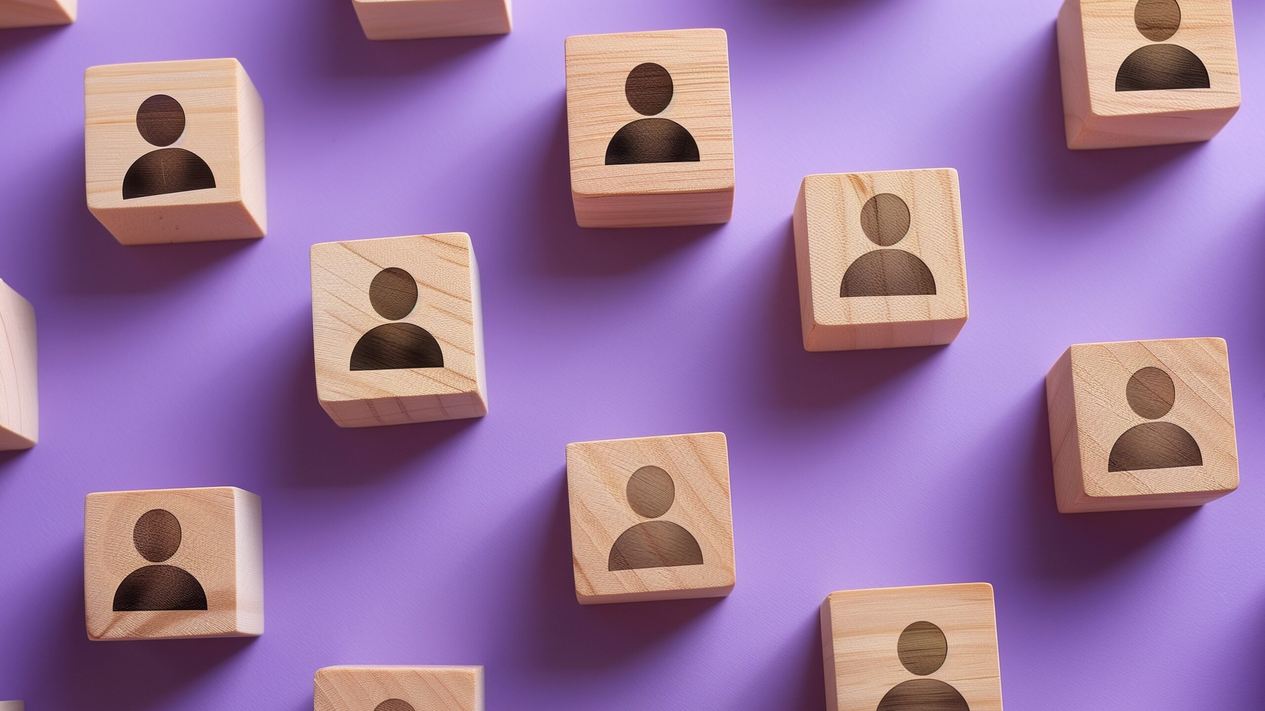 Wooden blocks with person icons on a purple background, representing employee development or networking.