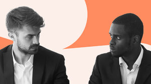 Image shows two men in business attire, sitting and looking intently at each other. Both appear serious and focused. The background features a contrasting orange and beige color scheme. The image suggests a moment of intense discussion or negotiation, reflecting a professional and possibly competitive interaction.
