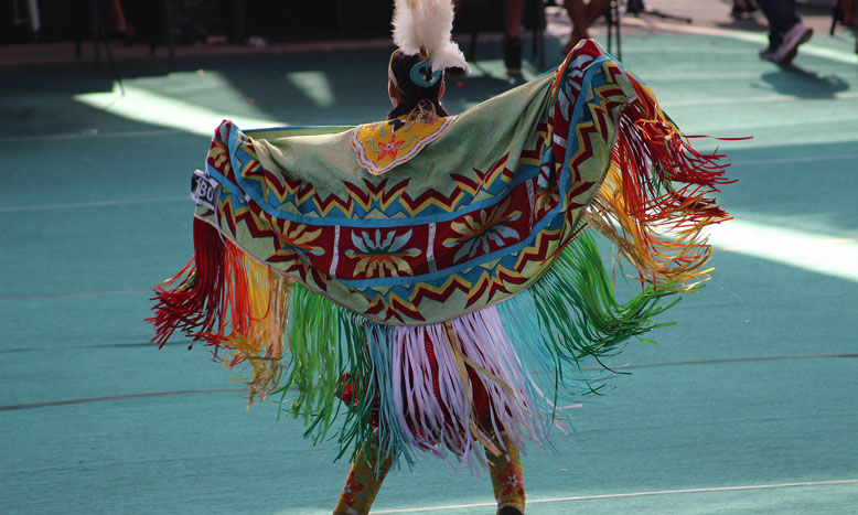 Indigenous dancer wearing colorful traditional regalia during a cultural celebration, showcasing movement, identity, and storytelling