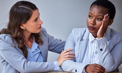 A colleague offering support to another in distress, symbolizing the importance of a trauma-informed approach in Employee Resource Groups (ERGs).